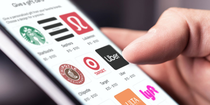 Close-up of a hand tapping a smartphone screen displaying app icons for Starbucks, Target, Uber, Chipotle, and Lyft (brand logos visible).